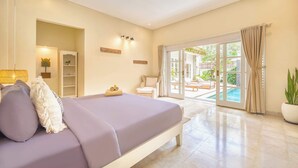 A bedroom with a bed, a chair, a small table with a towel, a shelf with decorative items, and a view of a pool through a glass door.