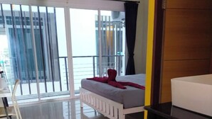 A modern hotel room with a bed, a desk, and a balcony with a view. - The HideAway Patong Beach (Patong)