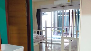 A hotel room with a large window, a balcony, a white bathtub, and a wooden door. - The HideAway Patong Beach (Patong)