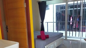 A hotel room with a bed, a small table, a red bucket, and a sliding glass door leading to a balcony. - The HideAway Patong Beach (Patong)