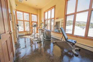 A gym with exercise equipment, large windows, and a view of a snowy landscape.