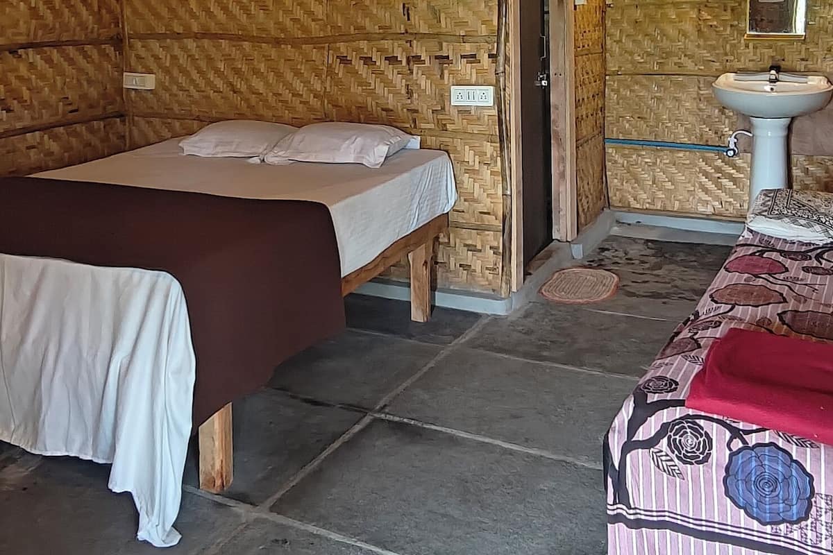 A room with a bed, a bedside table, a ceiling fan, a door, and a sink.