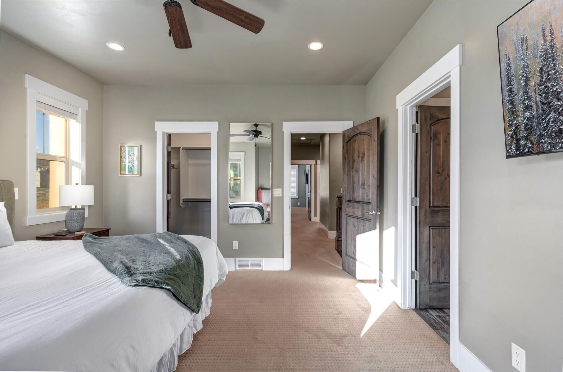 A bedroom with a bed, bedside table, lamp, and a painting on the wall.