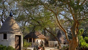 A rustic building with a conical roof, surrounded by trees and a pathway. - Toro River by Newmark (Makalali Game Reserve)