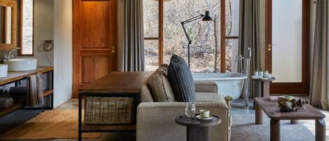 A cozy living room with a sofa, a coffee table, a side table, and a bathtub.