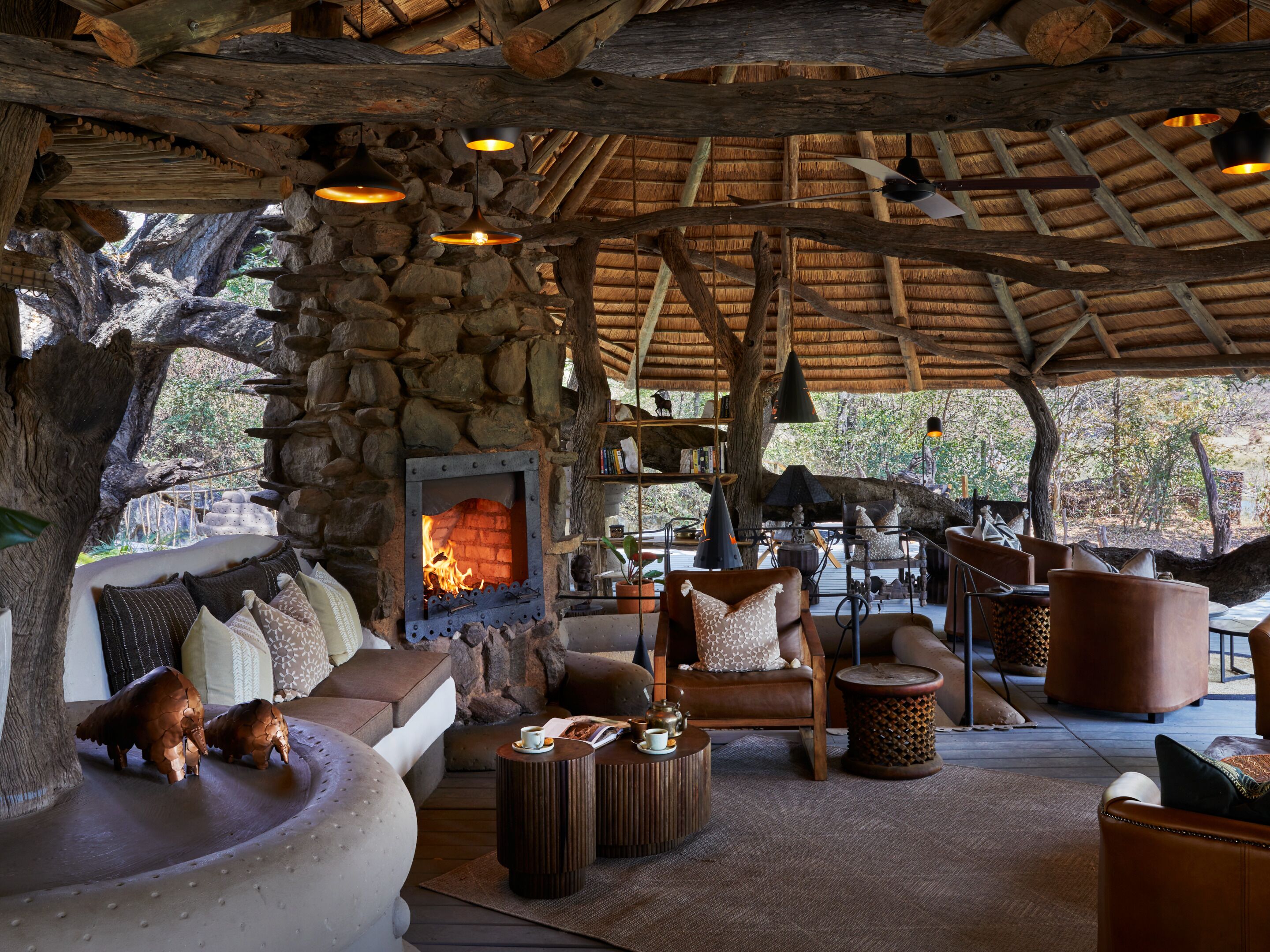 A rustic lounge area with a stone fireplace, leather seating, and wooden beams.