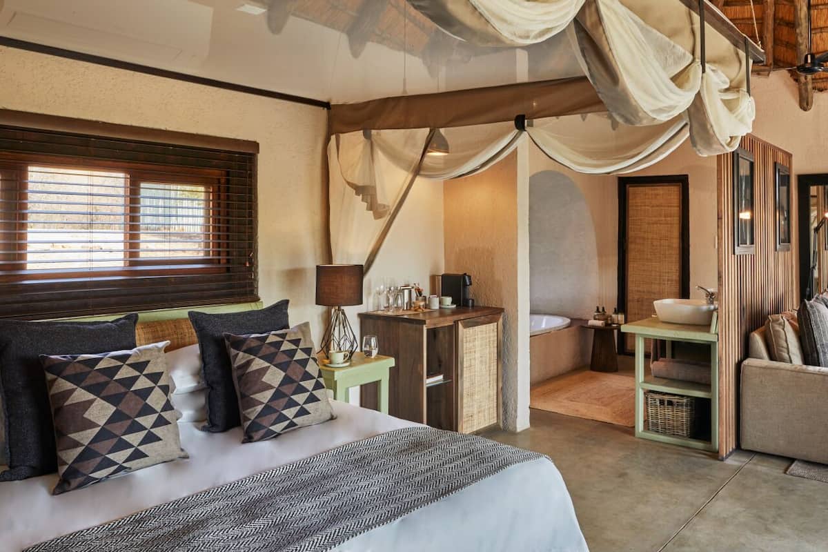 Une chambre à coucher avec un lit, une table de chevet, une lampe et une vue sur la salle de bain.