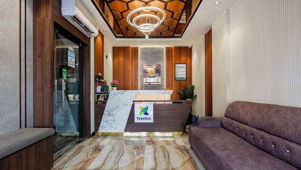 A reception area with a marble counter, a logo, and a sofa. - Treebo Sri Anand Residency (Chennai)