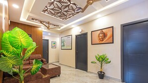 A modern lobby with a marble floor, a large green plant, a brown sofa, and a ceiling fan. - Treebo Sri Anand Residency (Chennai)