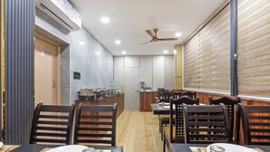 A modern dining area with wooden flooring, dark-toned chairs, and a central island with a bar setup. - Treebo Sri Anand Residency (Chennai)