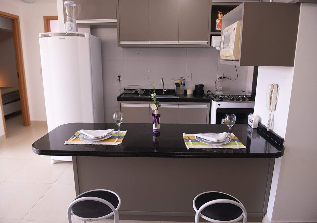 Cozinha moderna com ilha central, geladeira, micro-ondas e fogão.