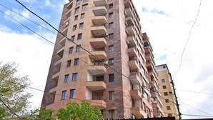 Un edificio residencial de varios pisos con balcones, unidades de aire acondicionado y un cielo despejado.