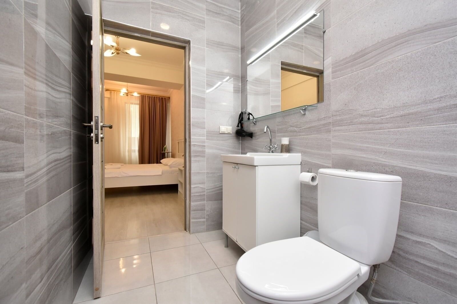 A modern bathroom with a toilet, sink, and mirror.