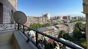 Un balcón con antena parabólica, con vistas a un paisaje urbano con edificios variados y cielos despejados.