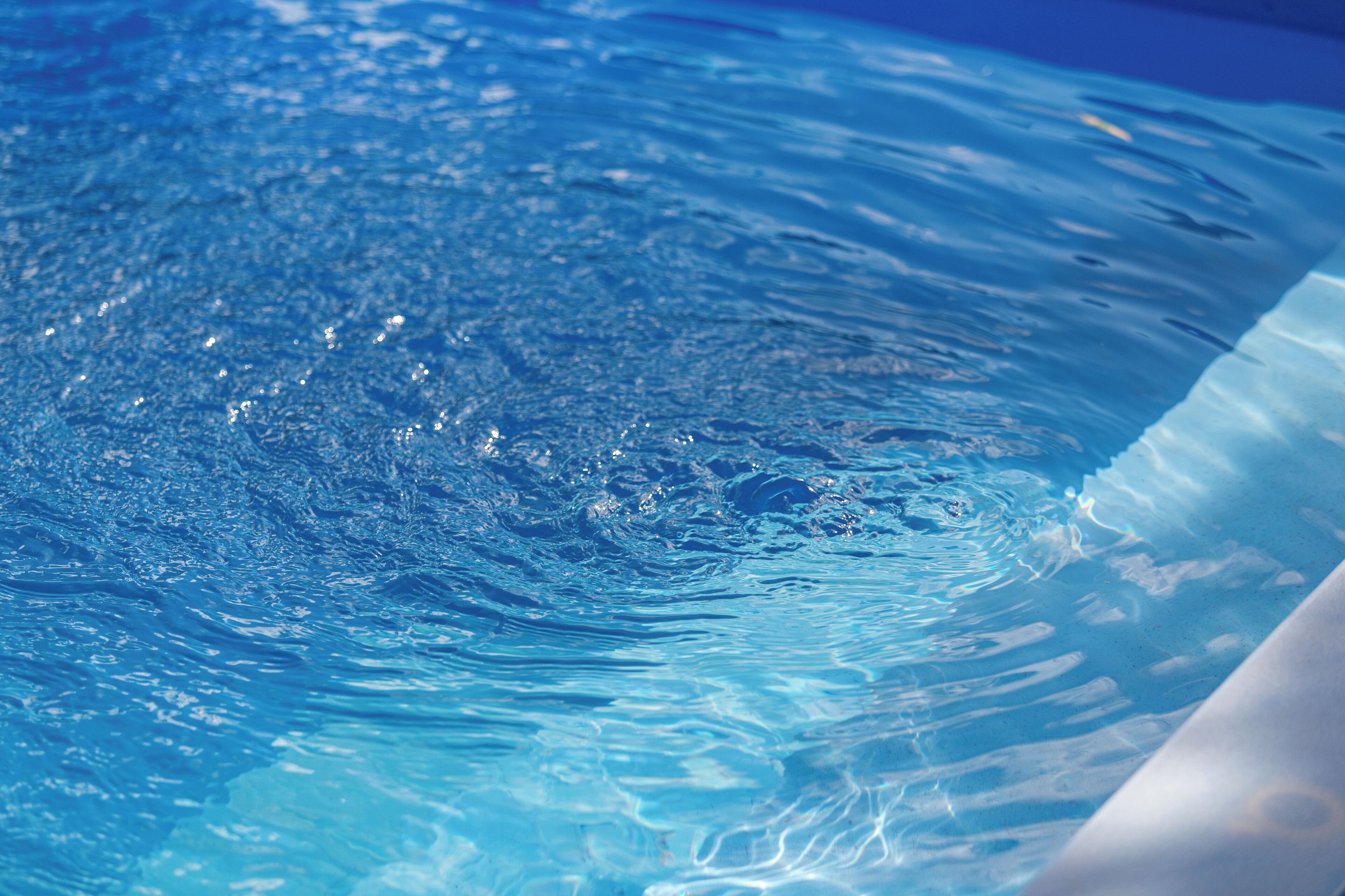 A clear view of a swimming pool with visible water ripples and a smooth, curved edge.