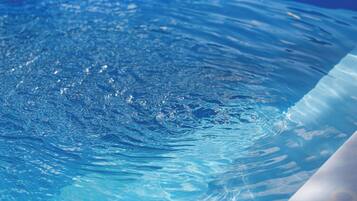 A clear view of a swimming pool with visible water ripples and a smooth, curved edge.