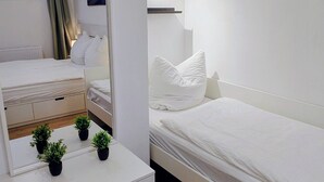 Une chambre à coucher moderne avec un grand miroir, un lit, une commode et une petite plante posée sur la commode.