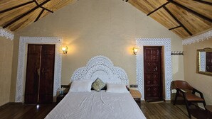 Un dormitorio con una cama grande, dos puertas, una silla y apliques de pared.