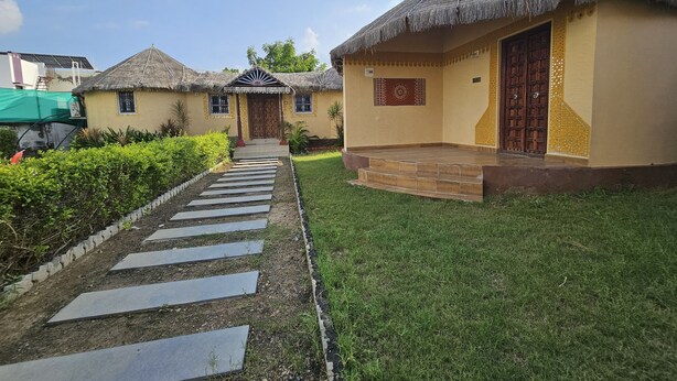 Una casa tradicional con techo de paja, un sendero empedrado que conduce a la entrada y un césped bien cuidado.