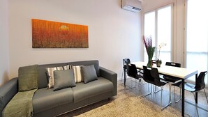 A modern living room with a gray sofa, a dining table with chairs, and a large abstract painting on the wall. - San Polo Apartment with Balcony  (Venice)