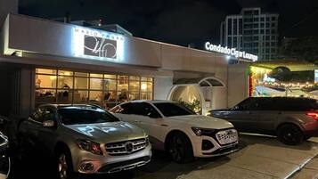A building with a sign reading "MARIO PAGAN" and another sign for "Condado Ciglar Lounge". Several cars are parked in front.