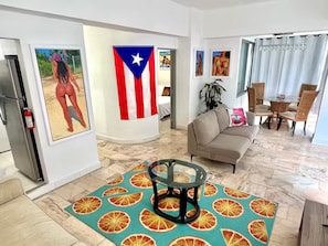 Uma sala de estar moderna com uma mesa de centro redonda de vidro, um sofá bege e um espaço de jantar com mesa e cadeiras.