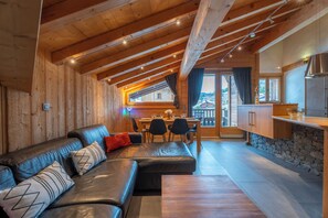 A wooden interior with a sofa, dining table, and kitchen area.