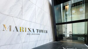 Eine Marmorwand mit dem Schriftzug "MARINA TOWER MELBOURNE" und einem Glastürdurchgang.