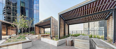 Een dakterras met houten banken, plantenbakken en een pergola.