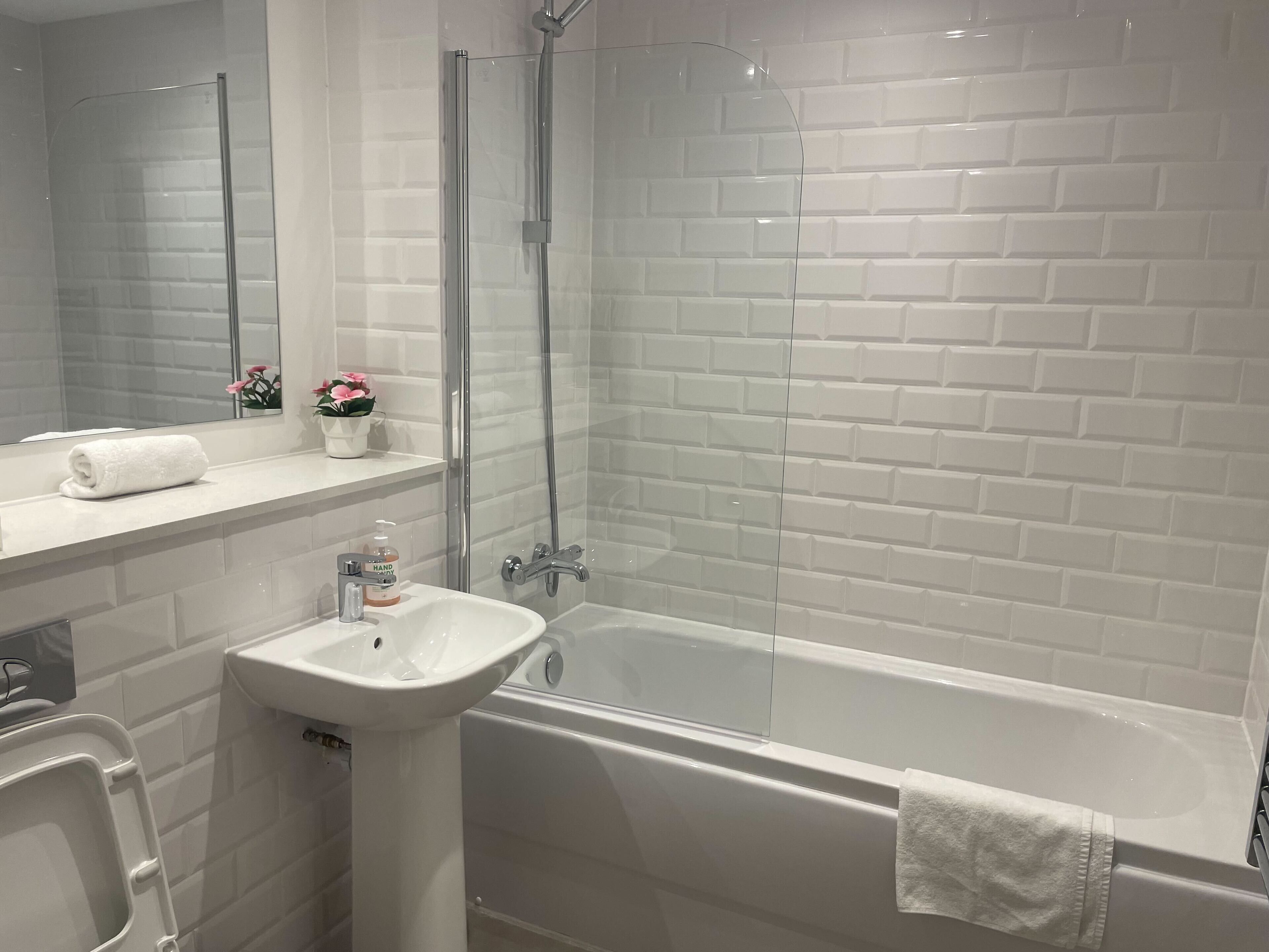 Une salle de bain moderne avec une douche à parois de verre, un lavabo blanc et une baignoire.