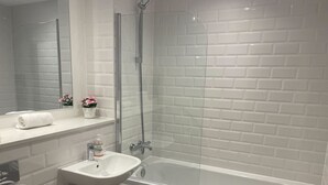 Une salle de bain moderne avec une douche à parois de verre, un lavabo blanc et une baignoire.