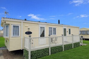 A mobile home with a fenced deck, a sign reading 'Granada,' and a number 'C27' on the gate.