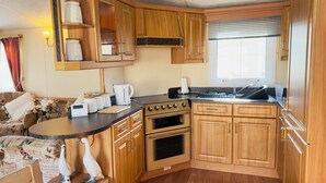 A compact RV kitchen with wooden cabinets, a stove, and a sink.