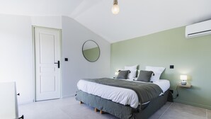 Een slaapkamer met een bed, nachtkastje, lamp en een deur.