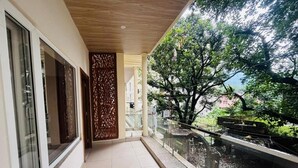 A corridor with a glass railing overlooking a garden with a water feature and trees. - Hotel Ramayan inn (Rishikesh)