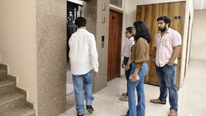A group of people standing in a hallway with a marble wall and a wooden door. - Hotel Ramayan inn (Rishikesh)