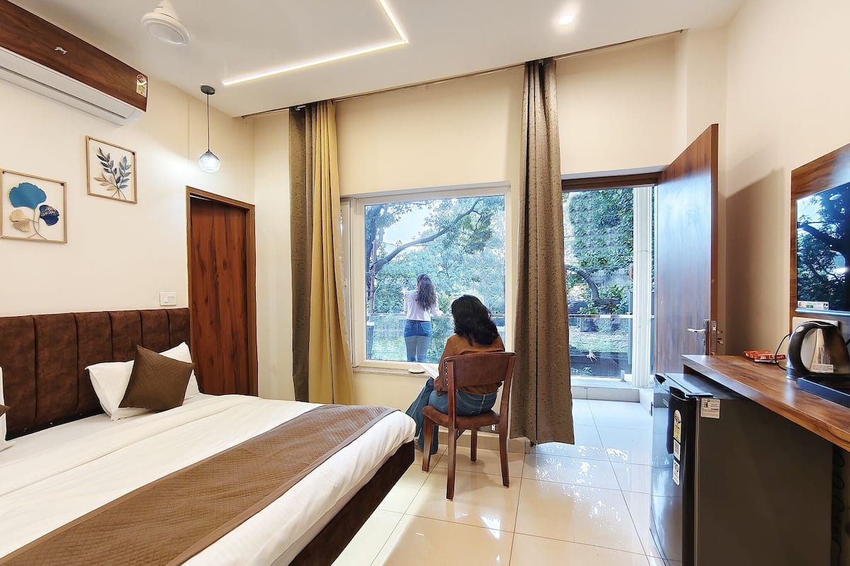 A hotel room with a bed, a desk, a TV, and a window with curtains.
