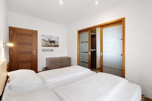 Une chambre à coucher comprenant un lit, une armoire en bois, une commode et un placard avec une porte coulissante en verre.