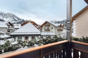 En snedækket landsby med bjergudsigt, traditionelle træhuse og en balkon.