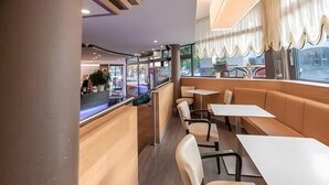 Interior de restaurante con cabinas, mesas, una barra y vista al exterior.