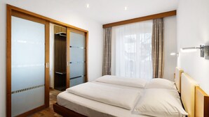 Un dormitorio con cama, armario y ventana con cortinas.