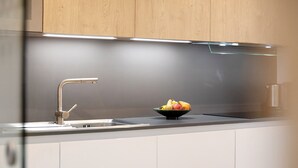 Una cocina moderna con un lavamanos de acero inoxidable, un cuenco de fruta y armarios de madera.