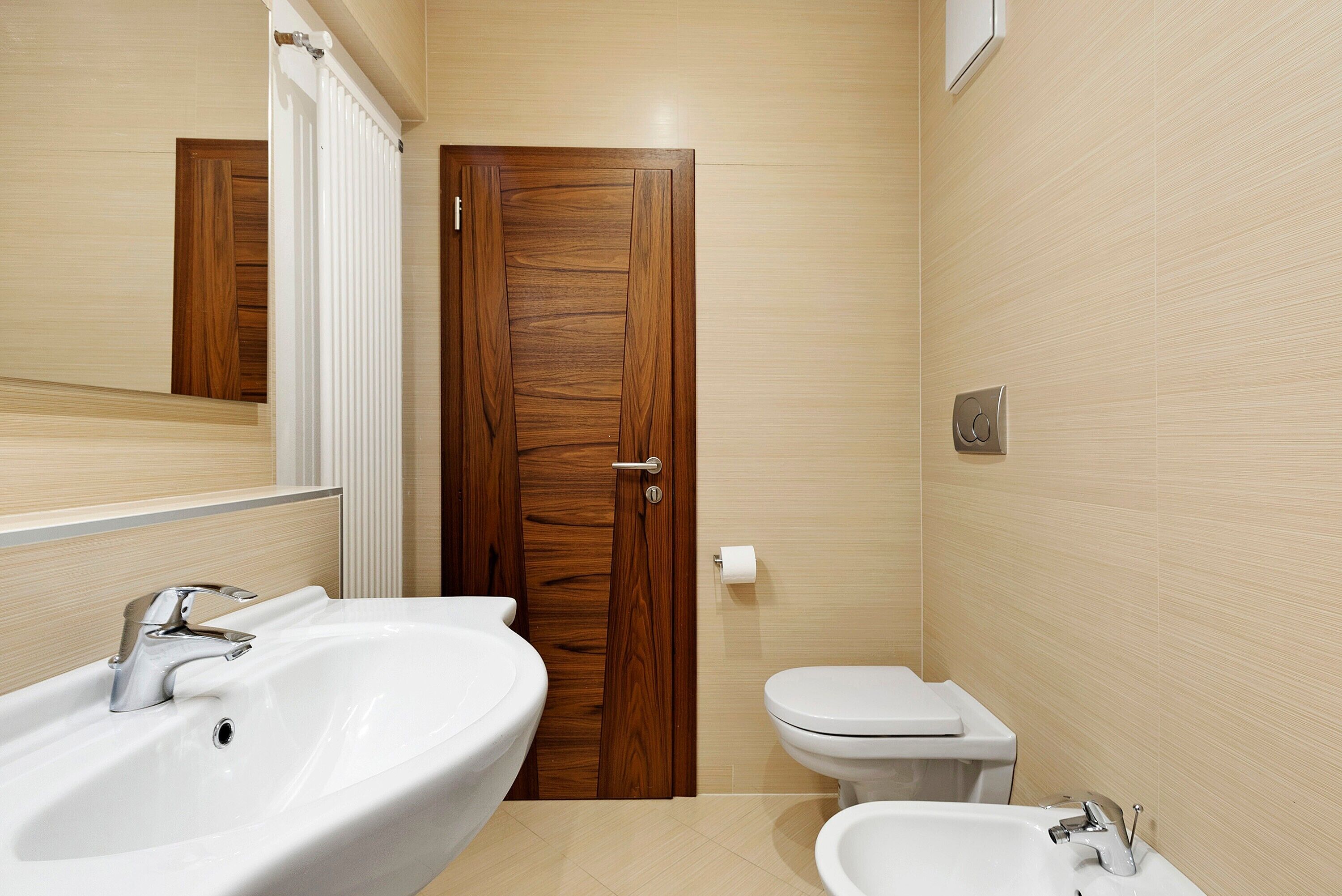 Ein Badezimmer mit Holztür, Waschbecken, Toilette und Bidet.