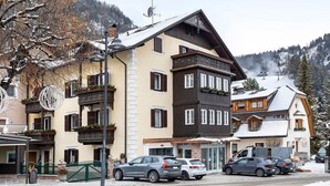 Un immeuble à plusieurs étages doté de balcons, avec une entrée bien visible, et une montagne enneigée en arrière-plan.