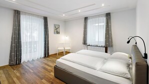 Une chambre à coucher avec un lit, deux chaises, une lampe et un tableau au mur.