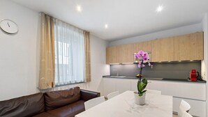 Une cuisine moderne avec des meubles en bois, un plan de travail blanc et un coin repas comprenant une table et des chaises blanches.
