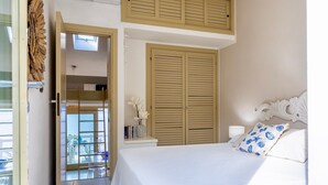Een slaapkamer met een bed, een nachtkastje, een raam en een deur naar een balkon.