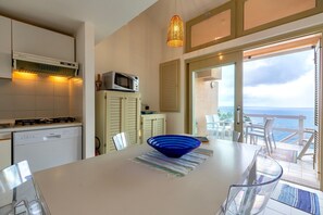 Une cuisine équipée d’un lave-vaisselle, d’un four à micro-ondes et d’un coin repas comprenant une table, des chaises et un saladier bleu.