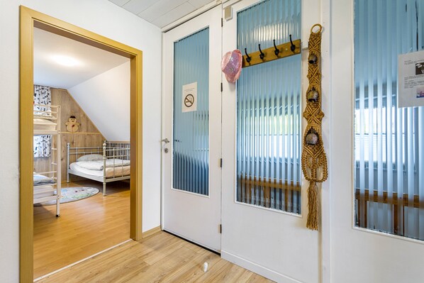 A room with a bunk bed, a door with frosted glass panels, and a decorative macrame piece.