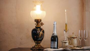 A table with a decorative lamp, a bottle of wine, a candle, and a teapot.